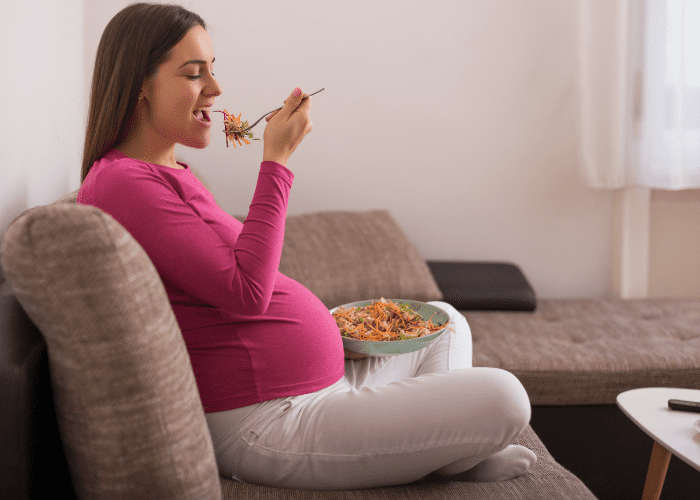 pregnant woman eating a plate of salad