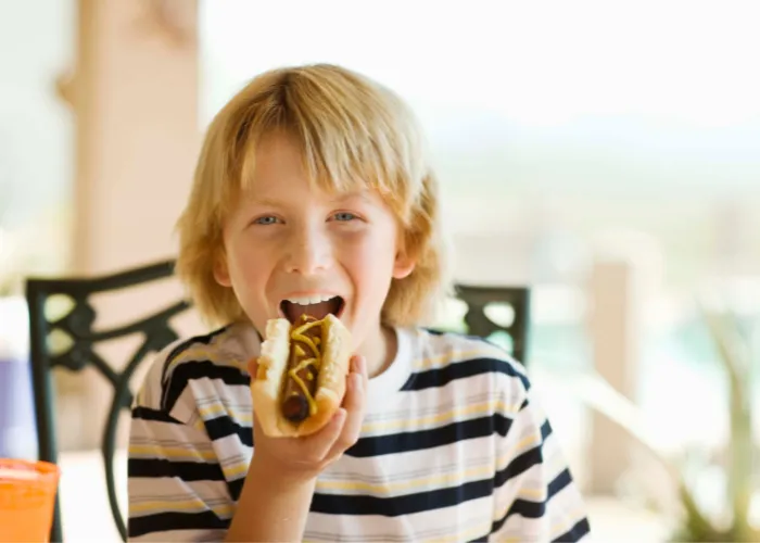  a young boy eating a hotdog