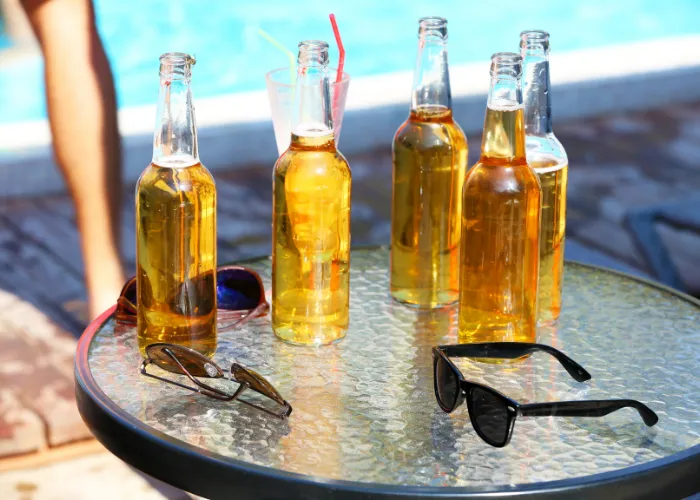5 bottles of beer on the table by the pool